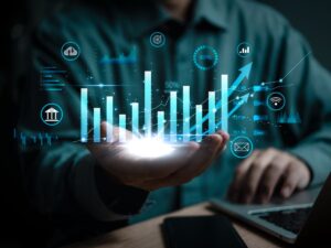 An image of a tech bar graph (upward trending) superimposed upon the hand of a person sitting at a computer. Represents operations support for construction teams.