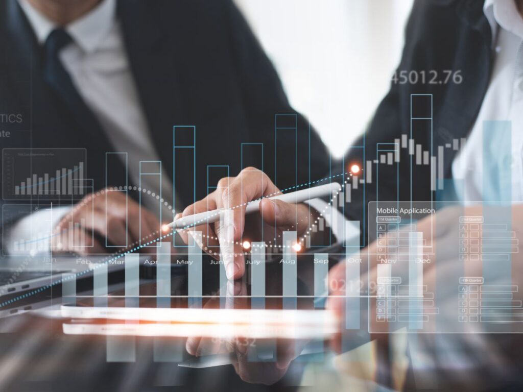 A businessman utilizes Procore Scalable Solutions to increase revenue in his construction business. Image includes a white growth bar graph superimposed over two businesspeople at a desk.