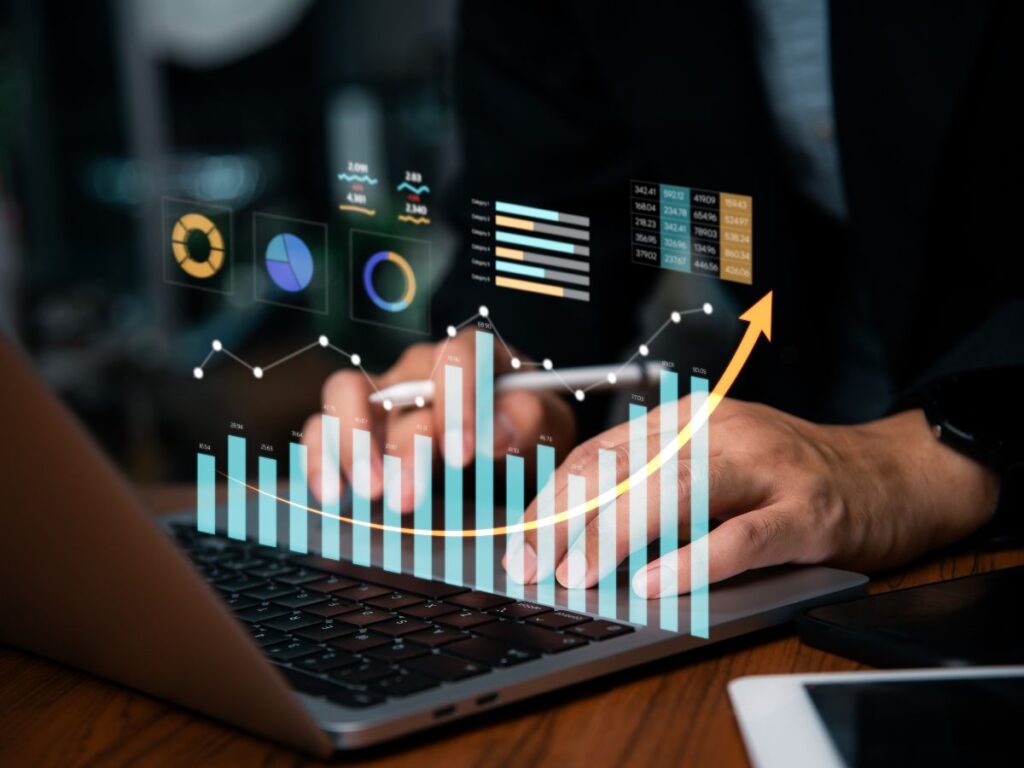 A tech image of an upward trending graph superimposed over an image of hands typing on a keyboard.